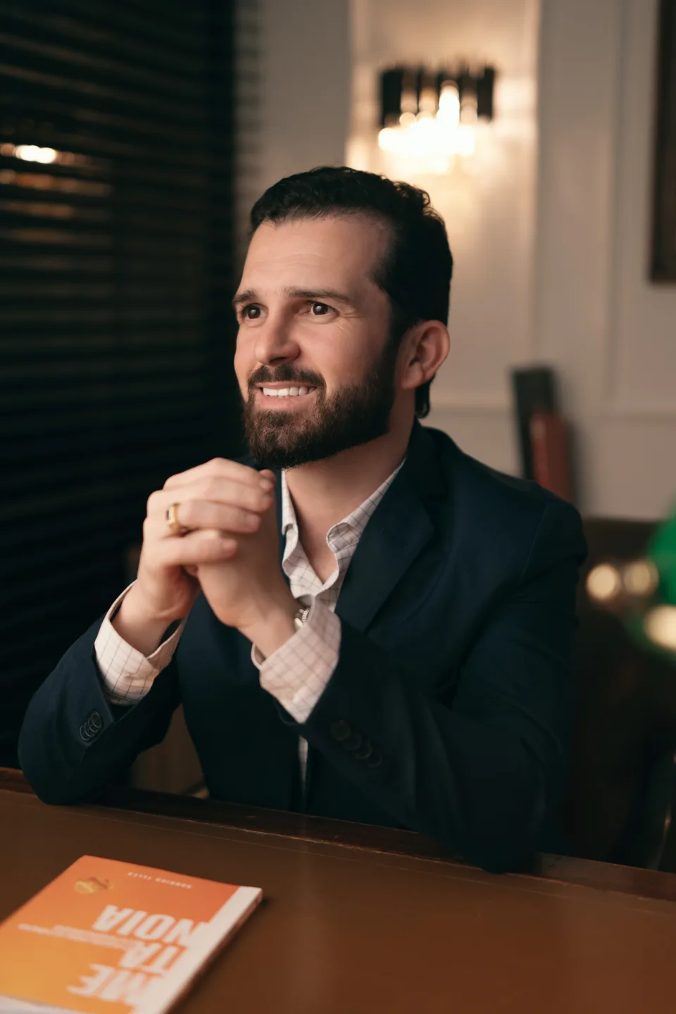 Rodrigo Teles, sentado à mesa, com as mãos apoiadas próximo ao rosto.