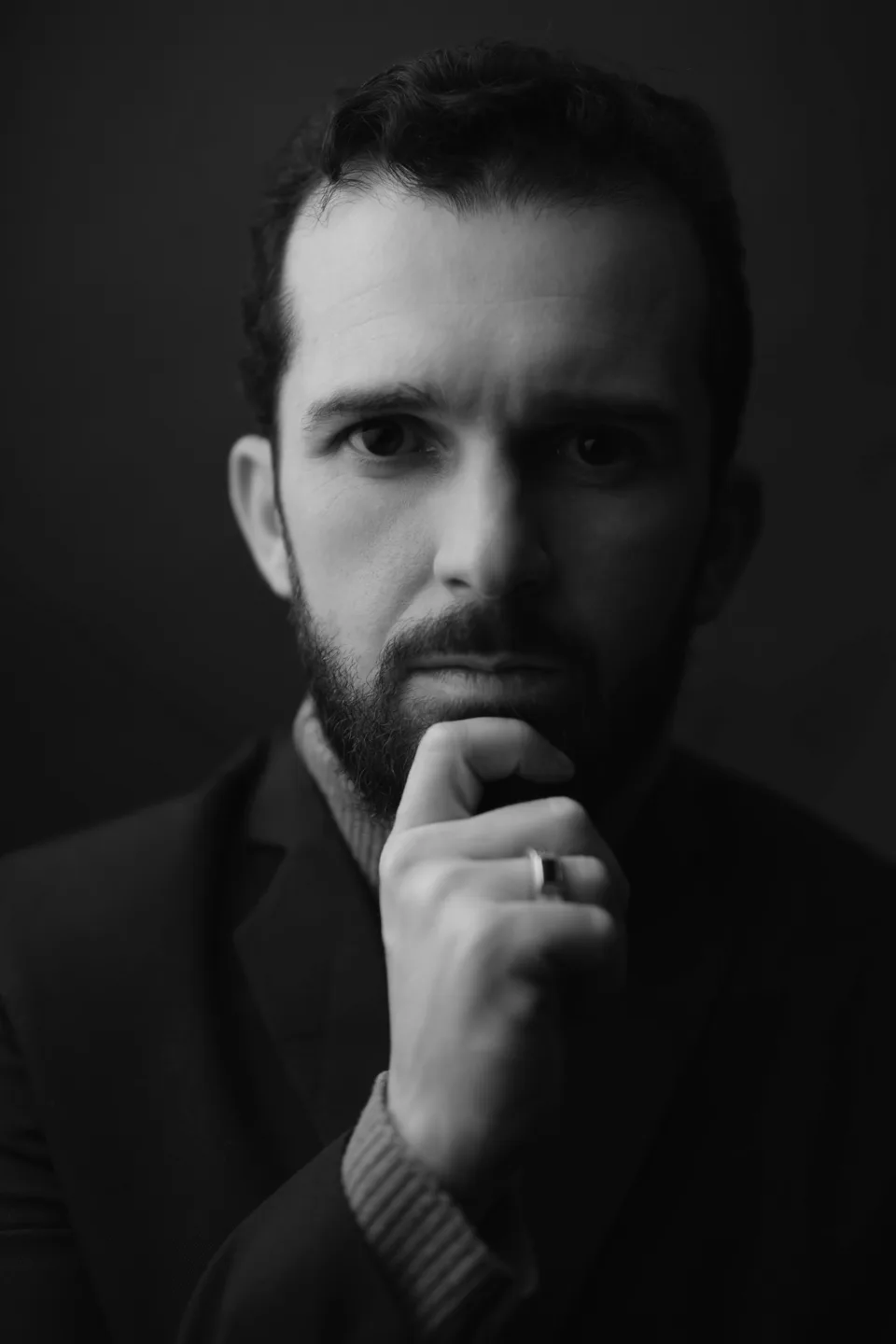 Retrato em preto e branco de Rodrigo Teles, com a mão apoiada no queixo.